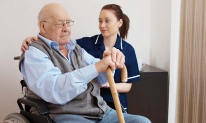 young nurse hugging senior man in wheelchair